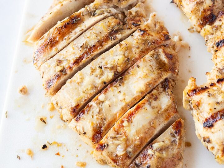 Grilled chicken with lemon and garlic on a cutting board.