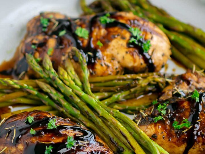 Chicken breasts and asparagus in a skillet.