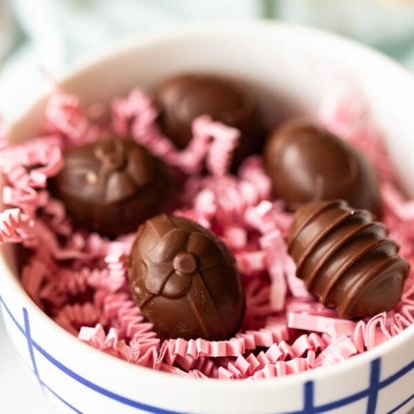 A bowl filled with chocolate cream eggs on pink crinkle paper.