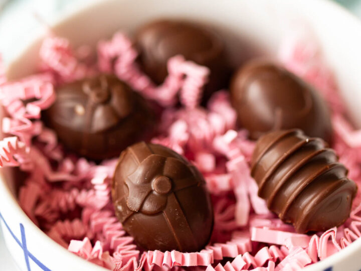 A bowl filled with chocolate cream eggs on pink crinkle paper.