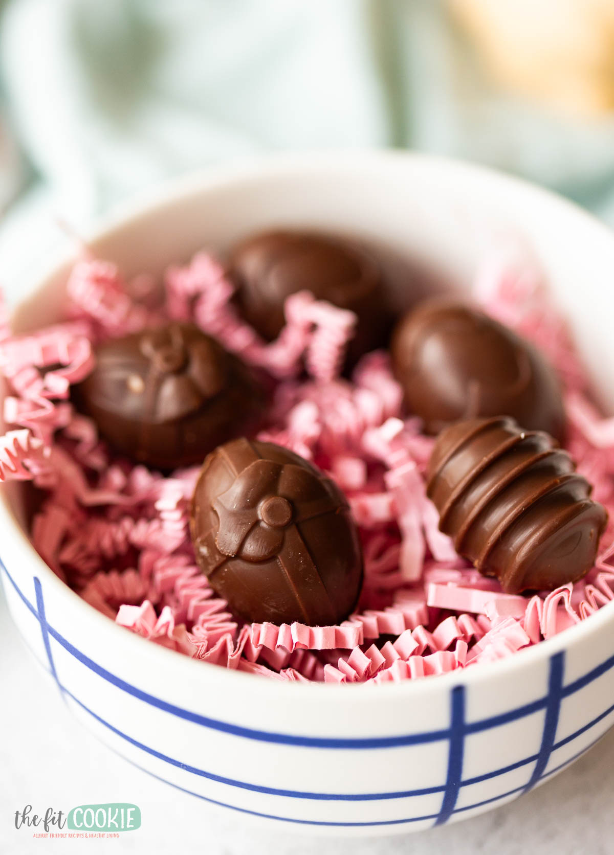 A bowl filled with chocolate cream eggs on pink crinkle paper.