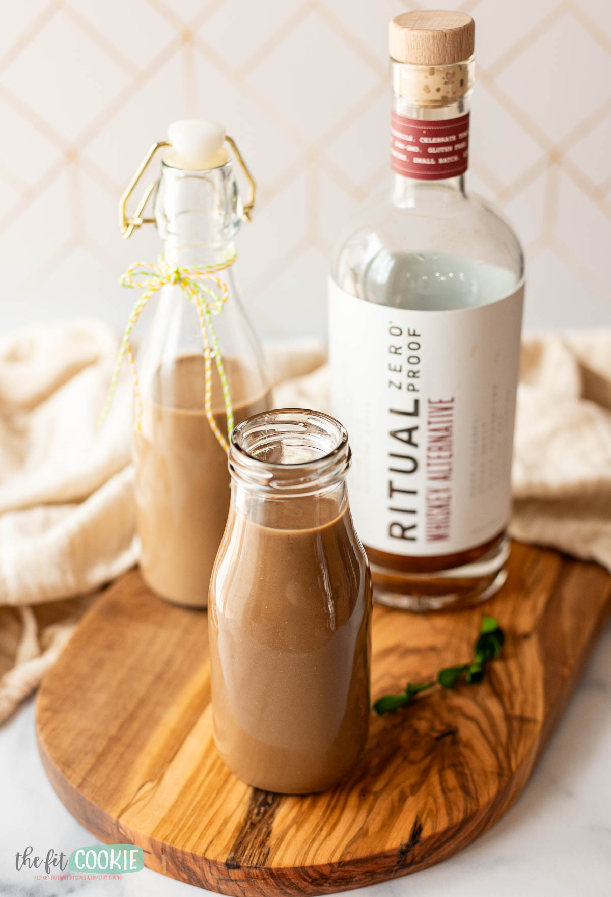 A bottle of homemade dairy-free irish cream on a wooden cutting board.