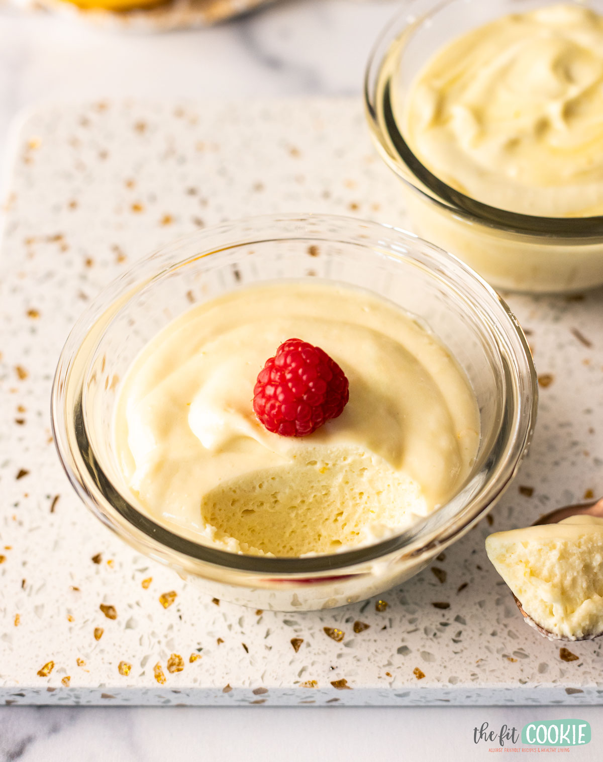 A bowl of vegan lemon mousse with a raspberry on top.