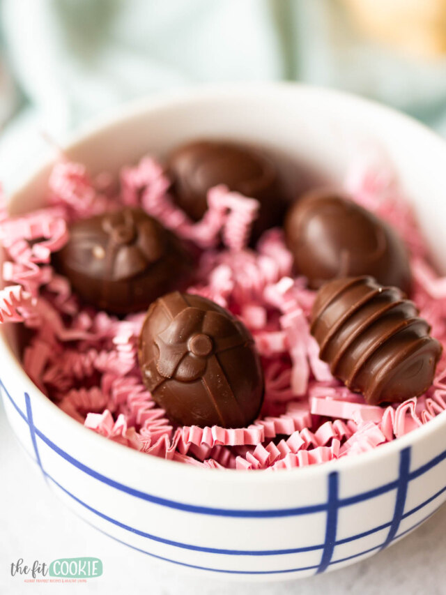 A bowl of chocolate easter eggs nestled in pink paper shreds.