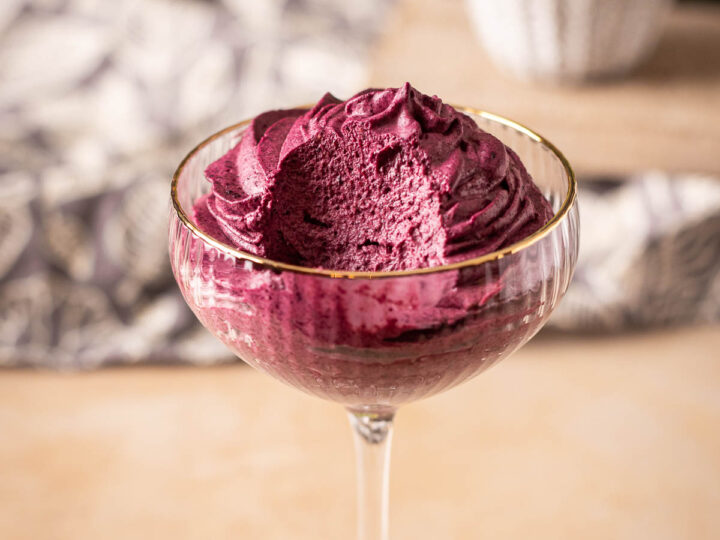 A scooped serving of purple acai berry sorbet in a glass dessert bowl.