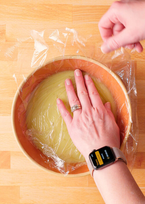 woman putting plastic wrap over lime pudding in a bowl. 