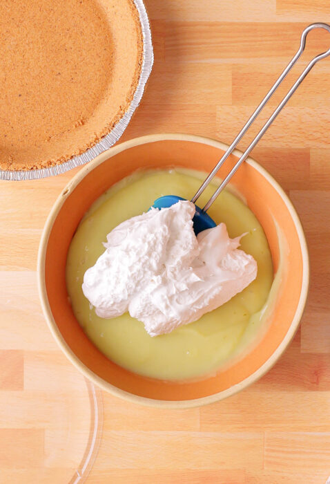 mixing dairy free cocowhip with lime pudding in a bowl. 