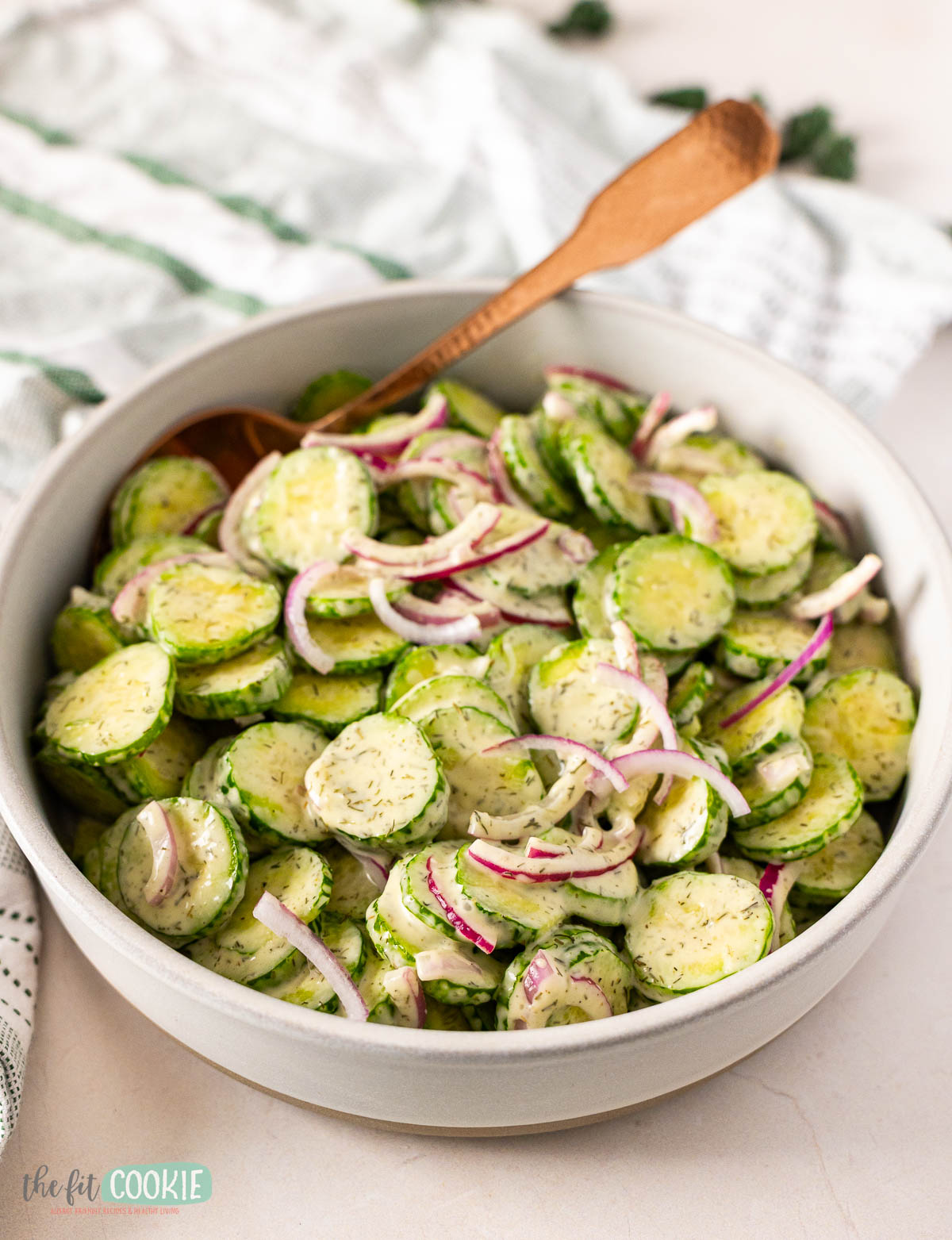 A bowl of cucumber salad with sliced cucumbers, red onions, and a creamy dressing.