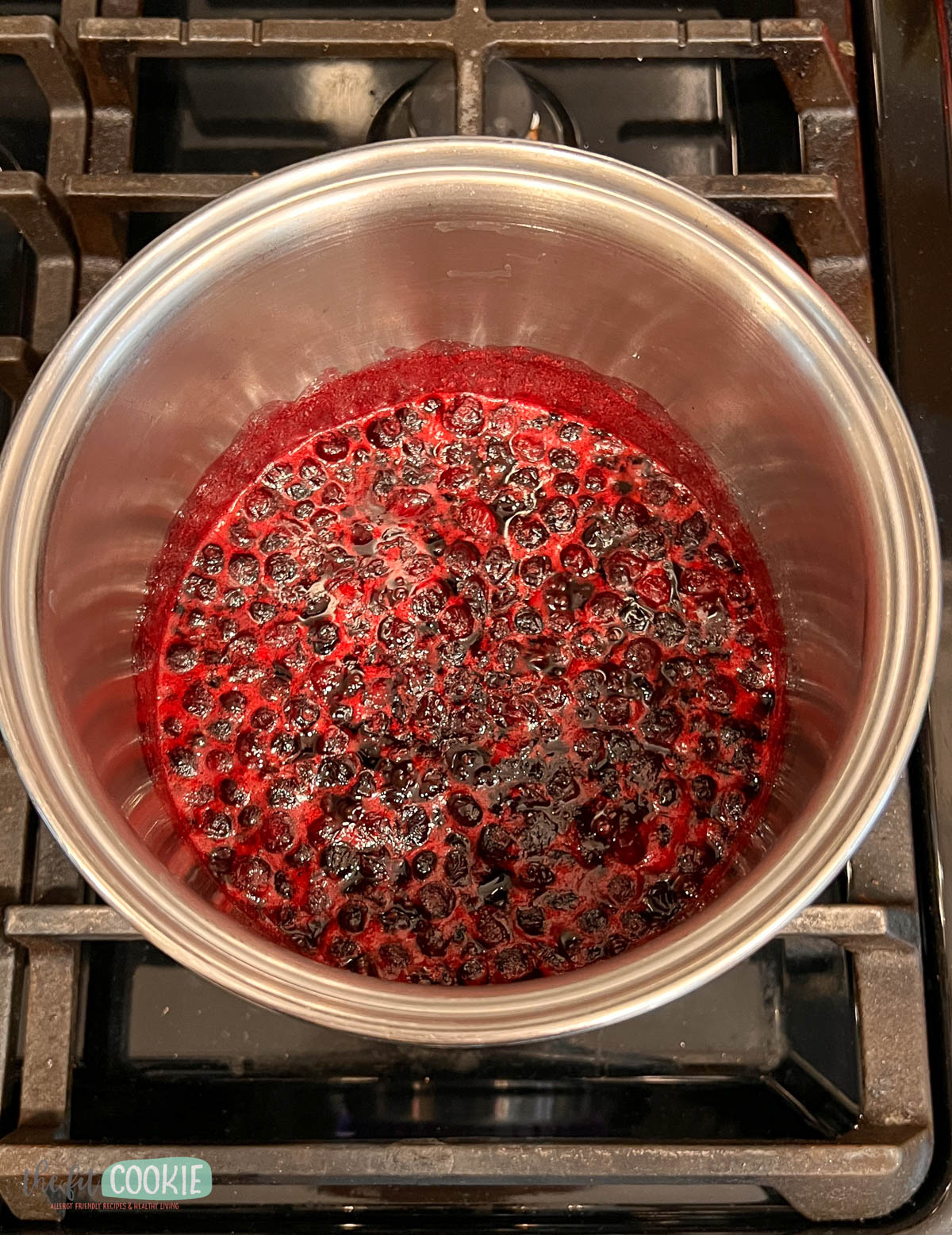 A stainless steel pot containing simmering huckleberries on the stove.
