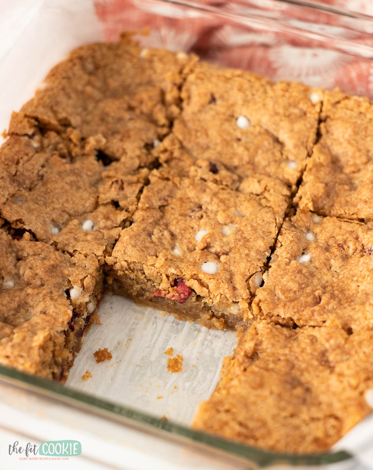 A glass baking dish with nine gluten free strawberry blondies, one piece missing.