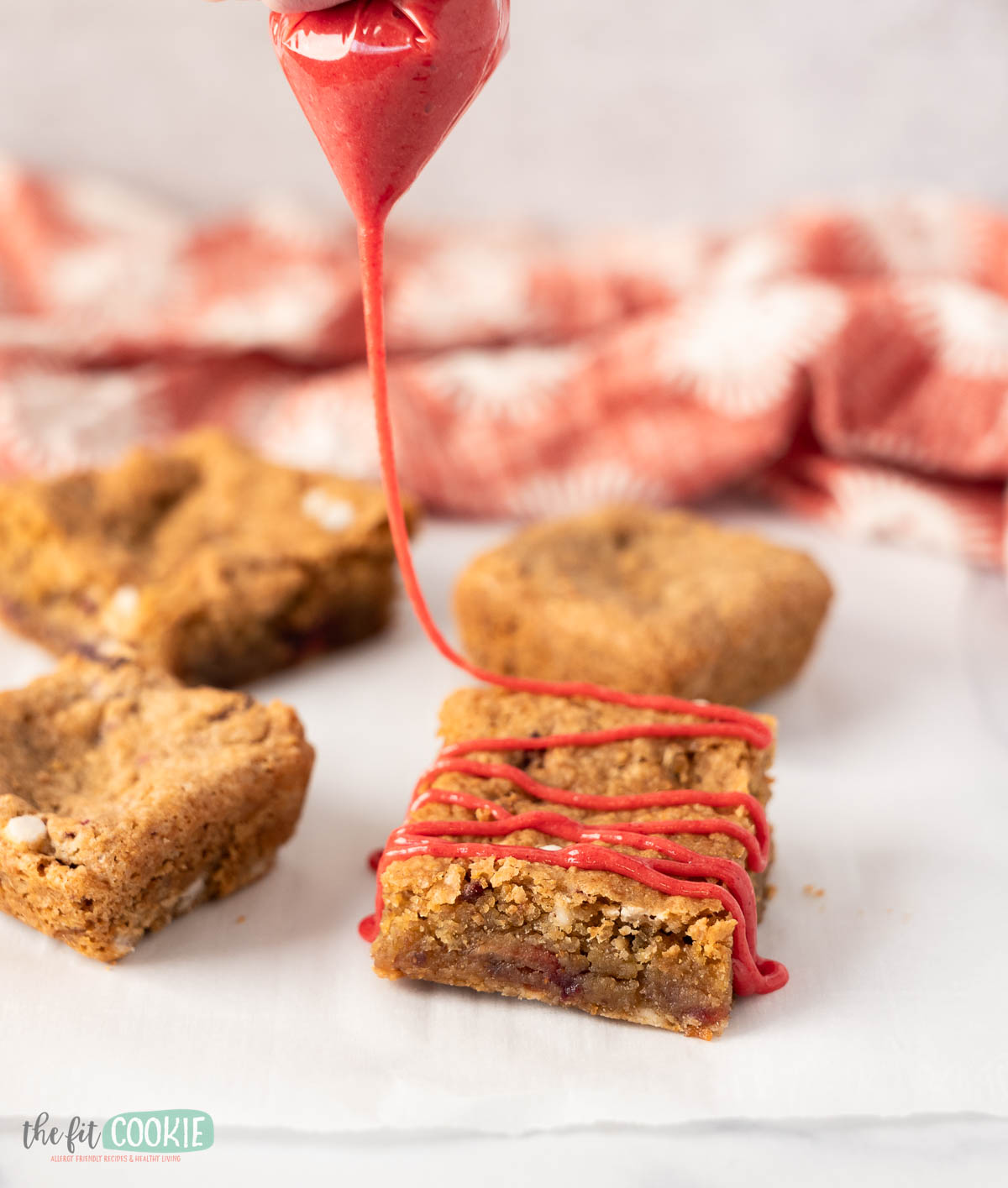 strawberry glaze being drizzled over a gluten free strawberry blondie bar.