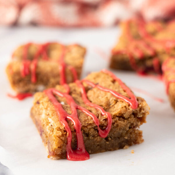 A close up of strawberry blondies showcases their golden, chewy texture and bursts of fresh strawberry pieces.