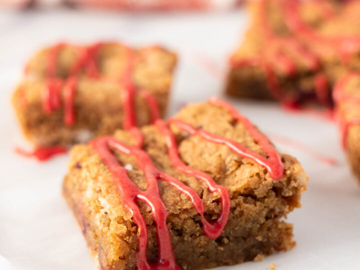 A close up of strawberry blondies showcases their golden, chewy texture and bursts of fresh strawberry pieces.