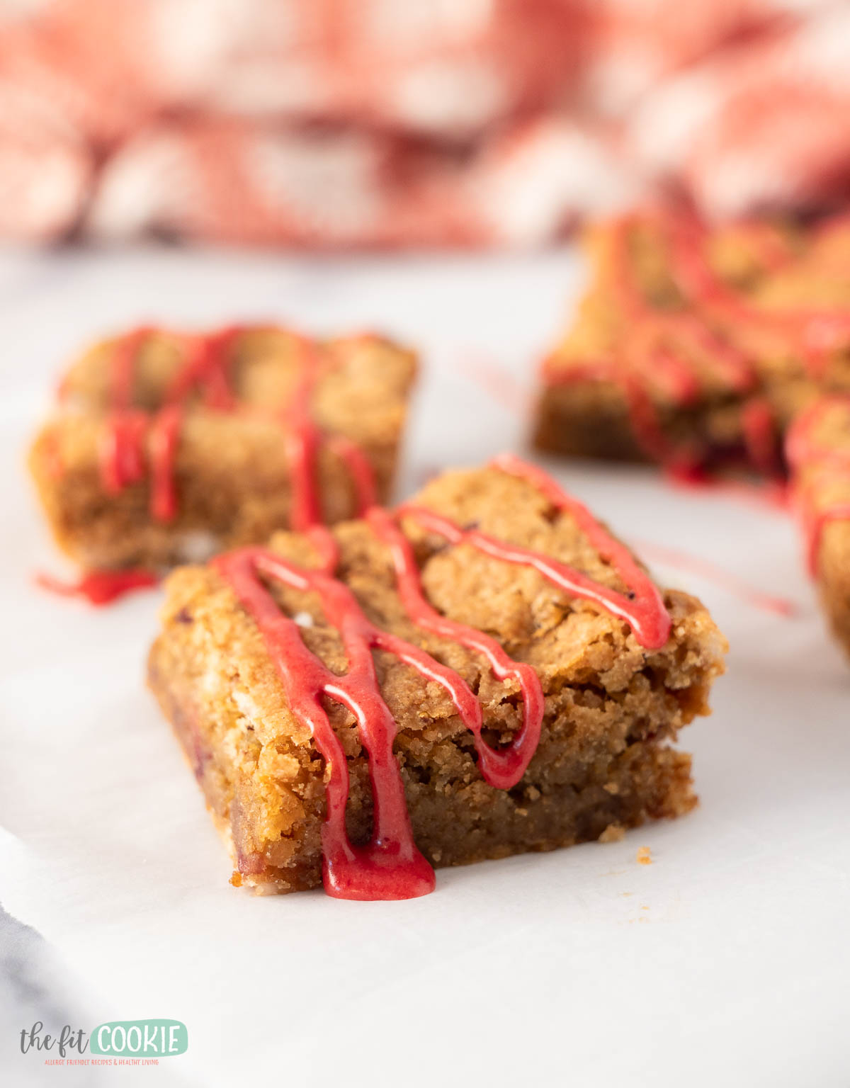 A close up of strawberry blondies showcases their golden, chewy texture and bursts of fresh strawberry pieces.
