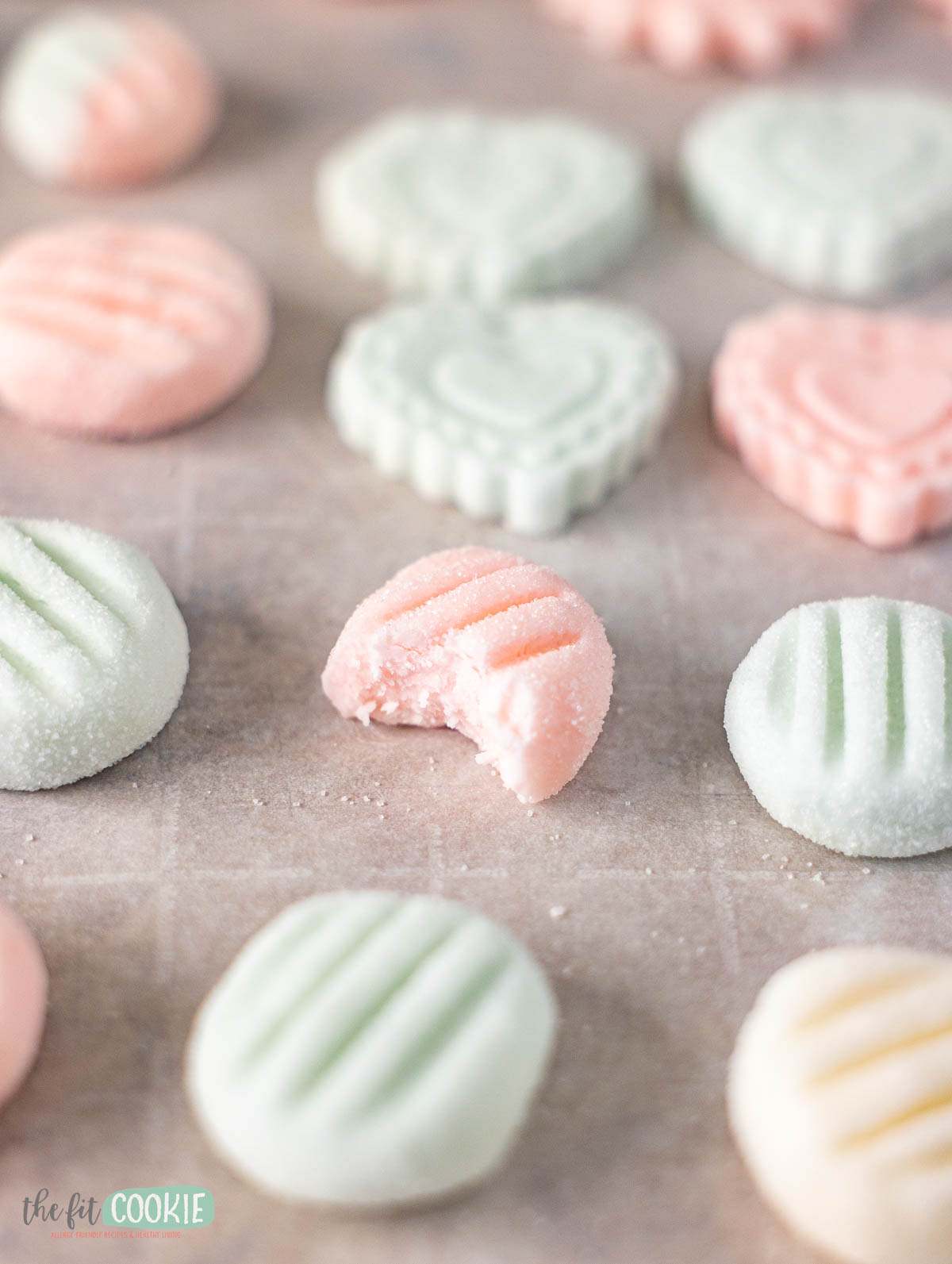 Pastel-colored Dairy Free Cream Cheese Mints, both round and heart-shaped, are arranged on parchment paper.