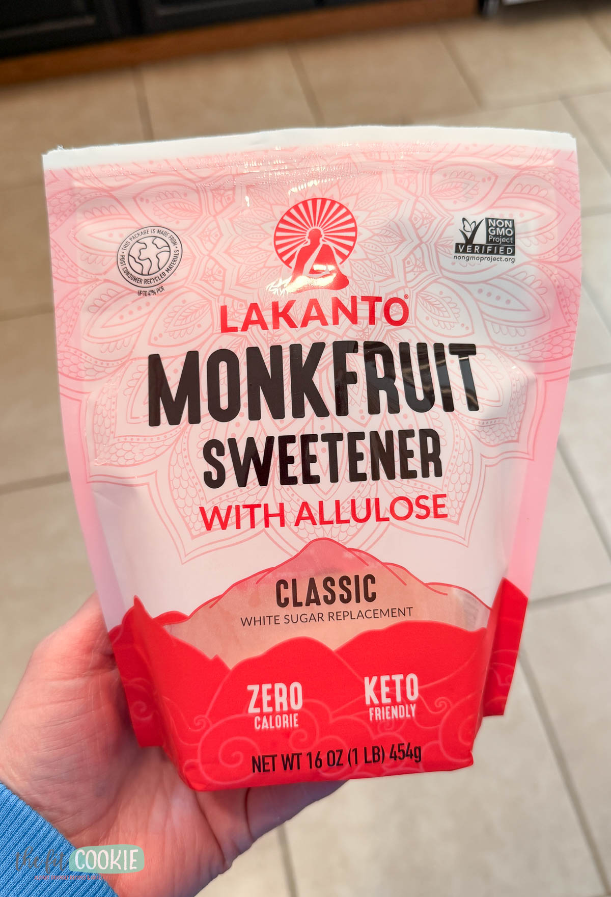 A hand holds a bag of Lakanto Monkfruit Sweetener with Allulose.