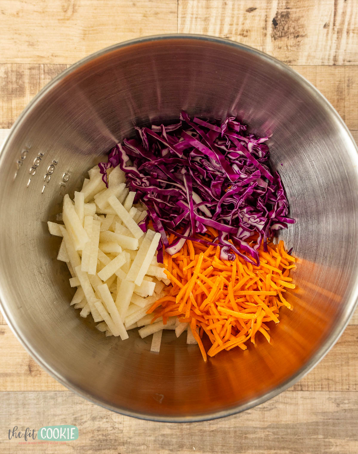 A metal mixing bowl containing ingredients for jicama salad.