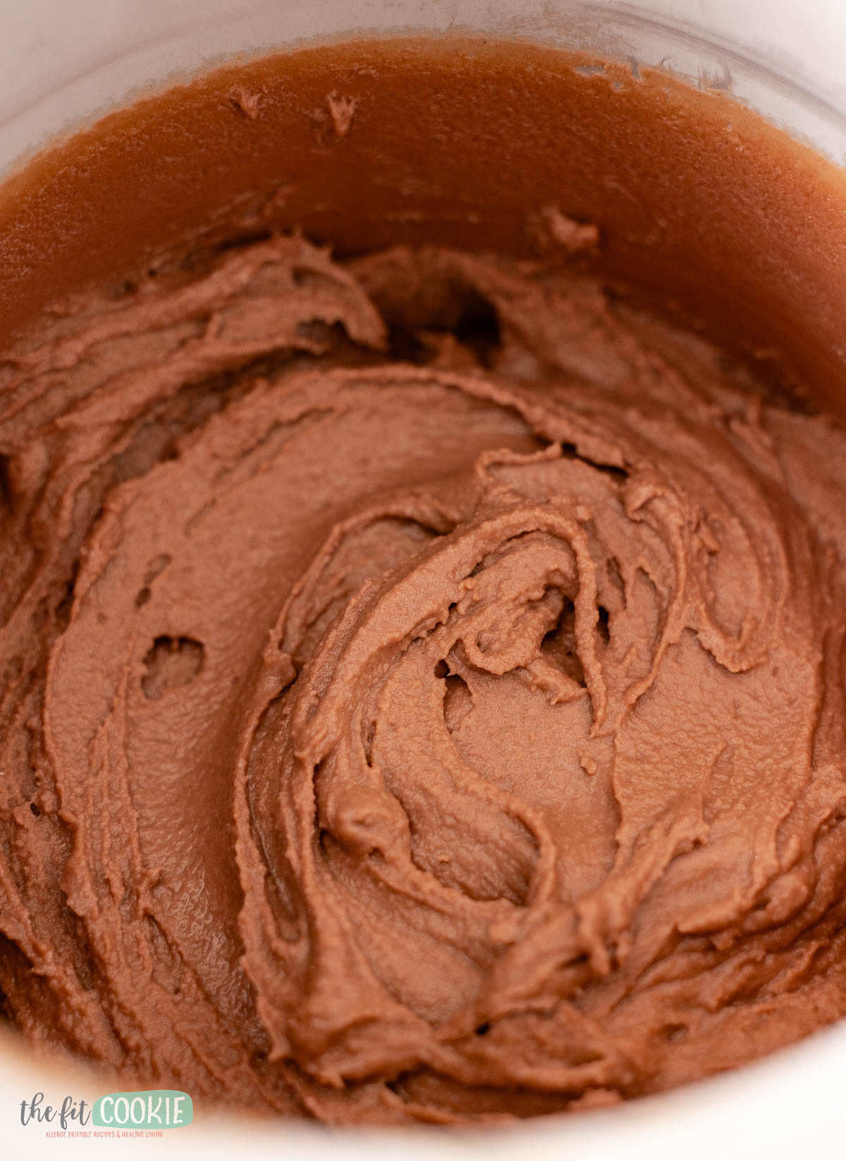 A close-up of photo of creamy vegan sugar free chocolate ice cream in an ice cream maker bowl.