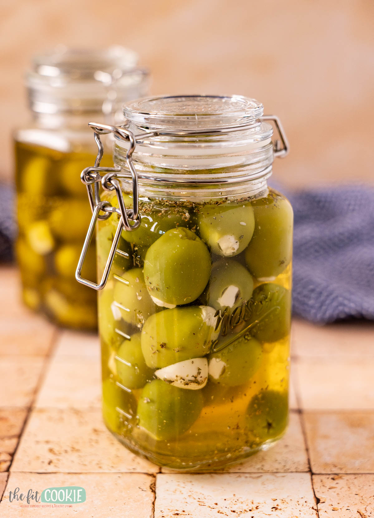 glass mason clamp jar filled with dairy free feta olives, herbs, garlic, and brine.