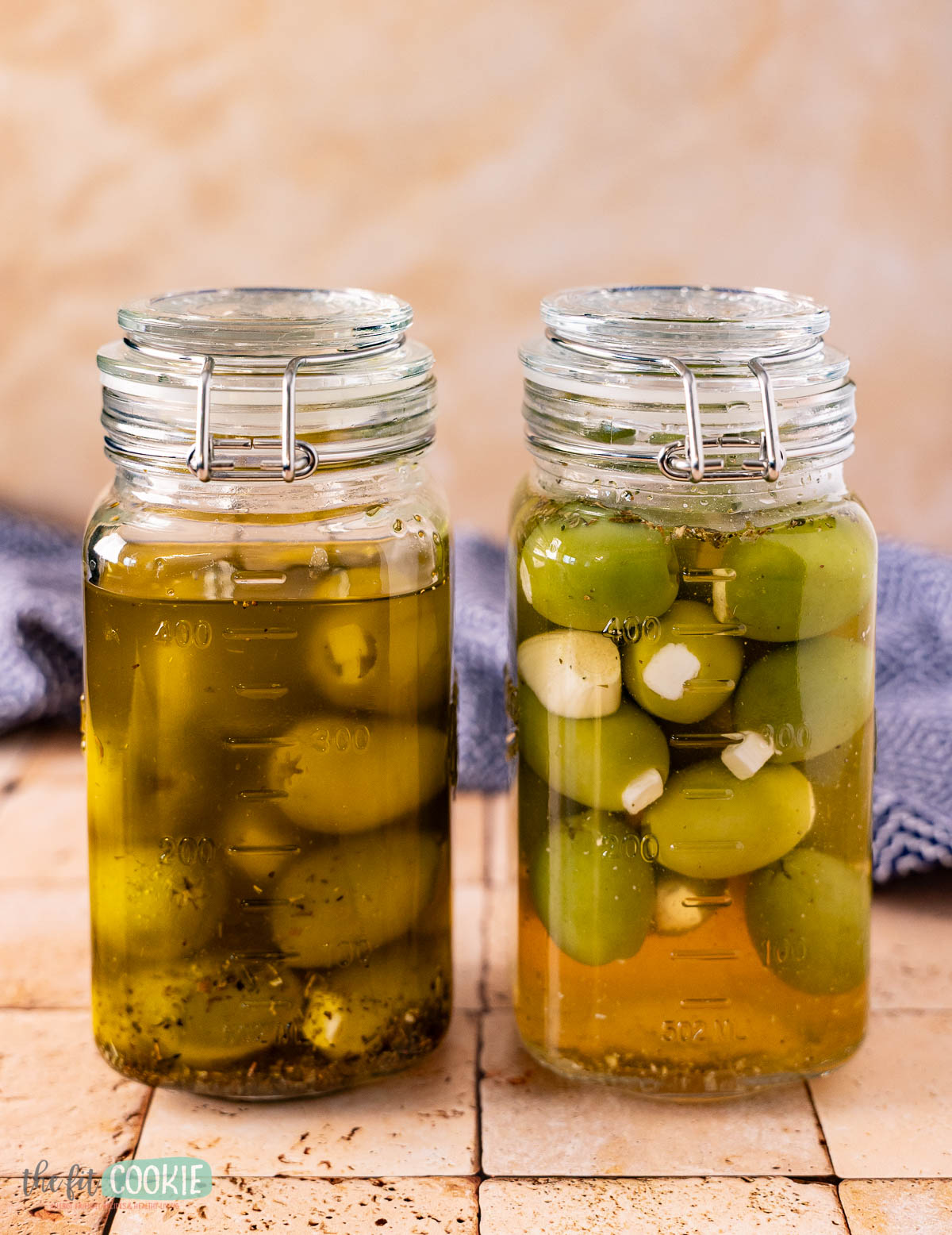 Two glass clamp jars filled with marinated olives, one jar in oil and one jar in brine.
