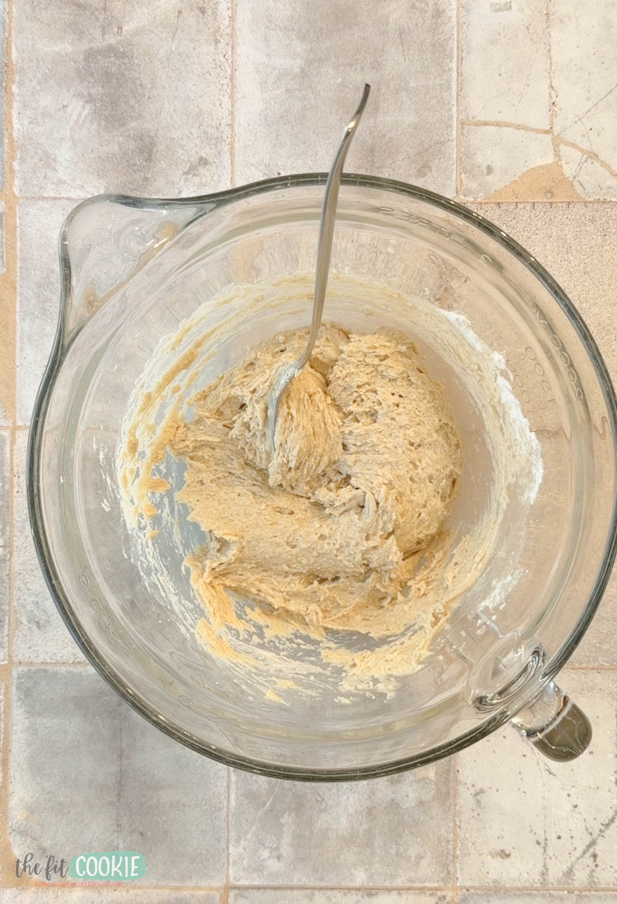 A glass mixing bowl with thick batter inside for making churros.