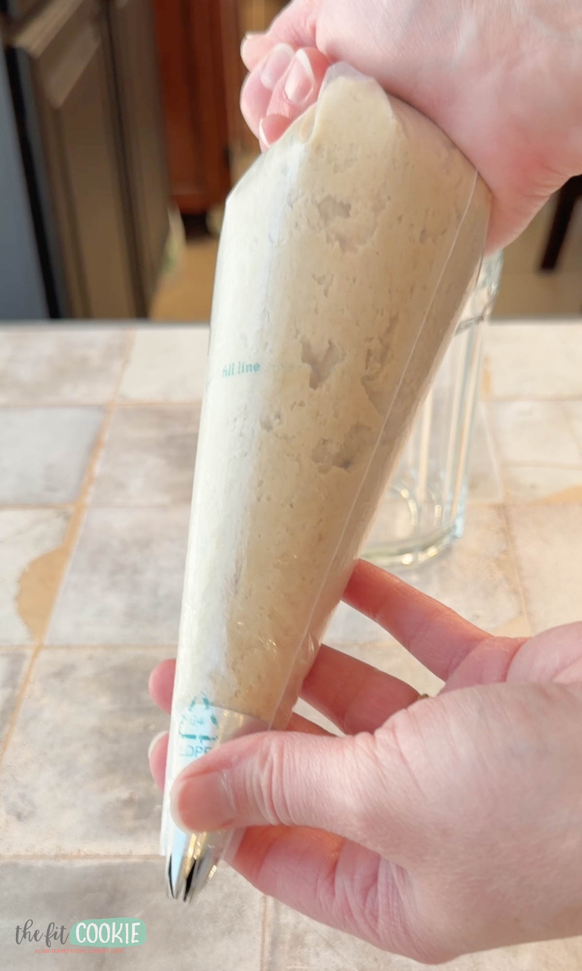 A hand holds a piping bag filled with gluten free churro batter/dough.