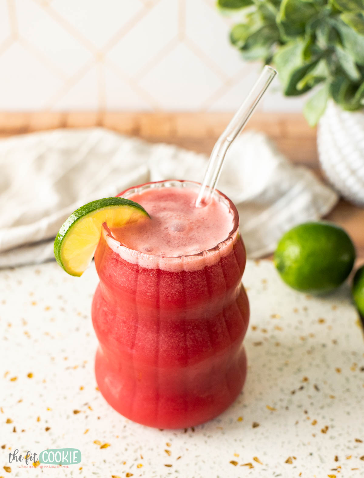 a glass filled with red dairy free cherry brazilian lemonade/limeade with a lime slice.