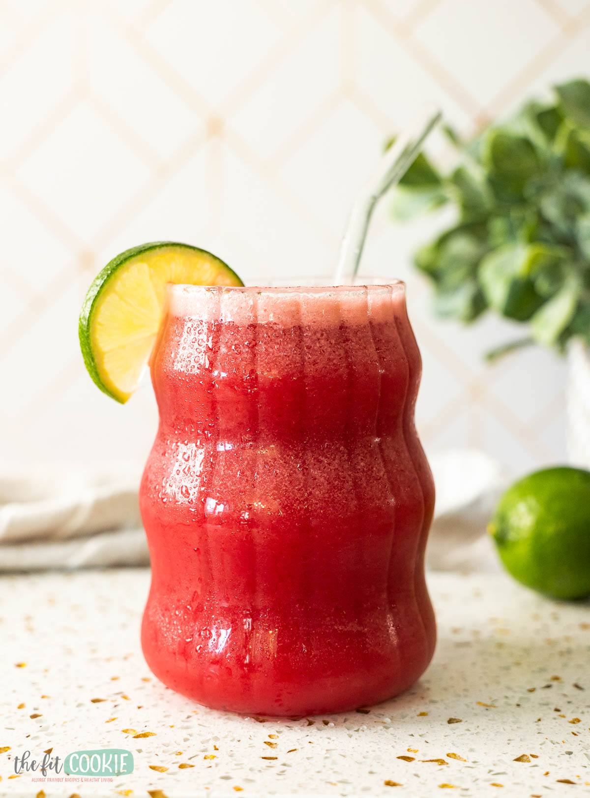 A dairy free cherry brazilian lemonade in a wavy glass with condensation on the outside of the glass. 
