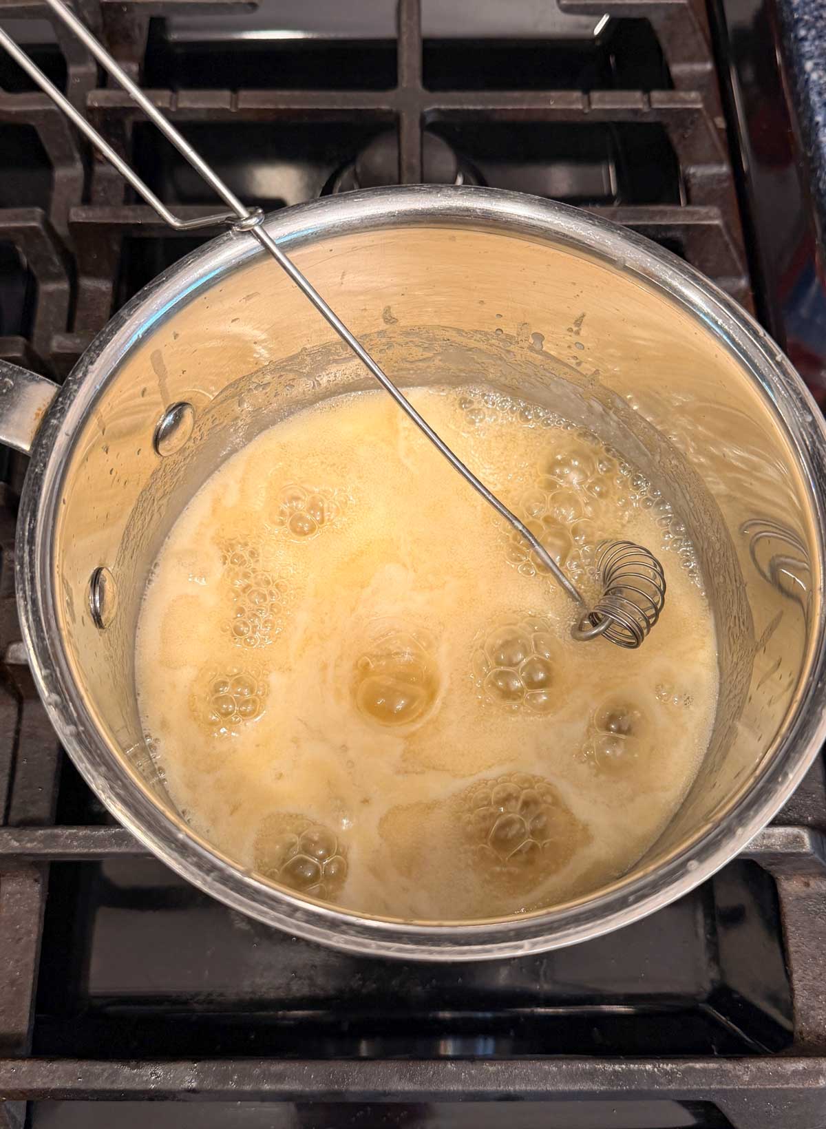 A saucepan with a whisk contains bubbling sugar and butter mixture.