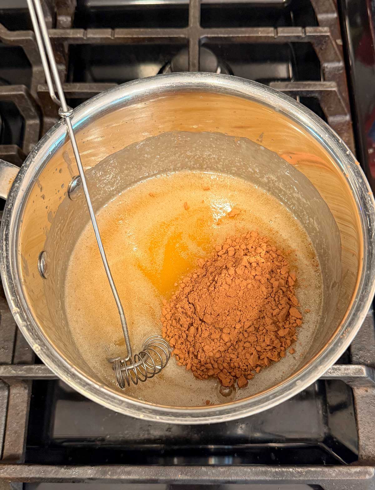 adding cocoa powder to the saucepan of cooked dairy free caramel sauce.