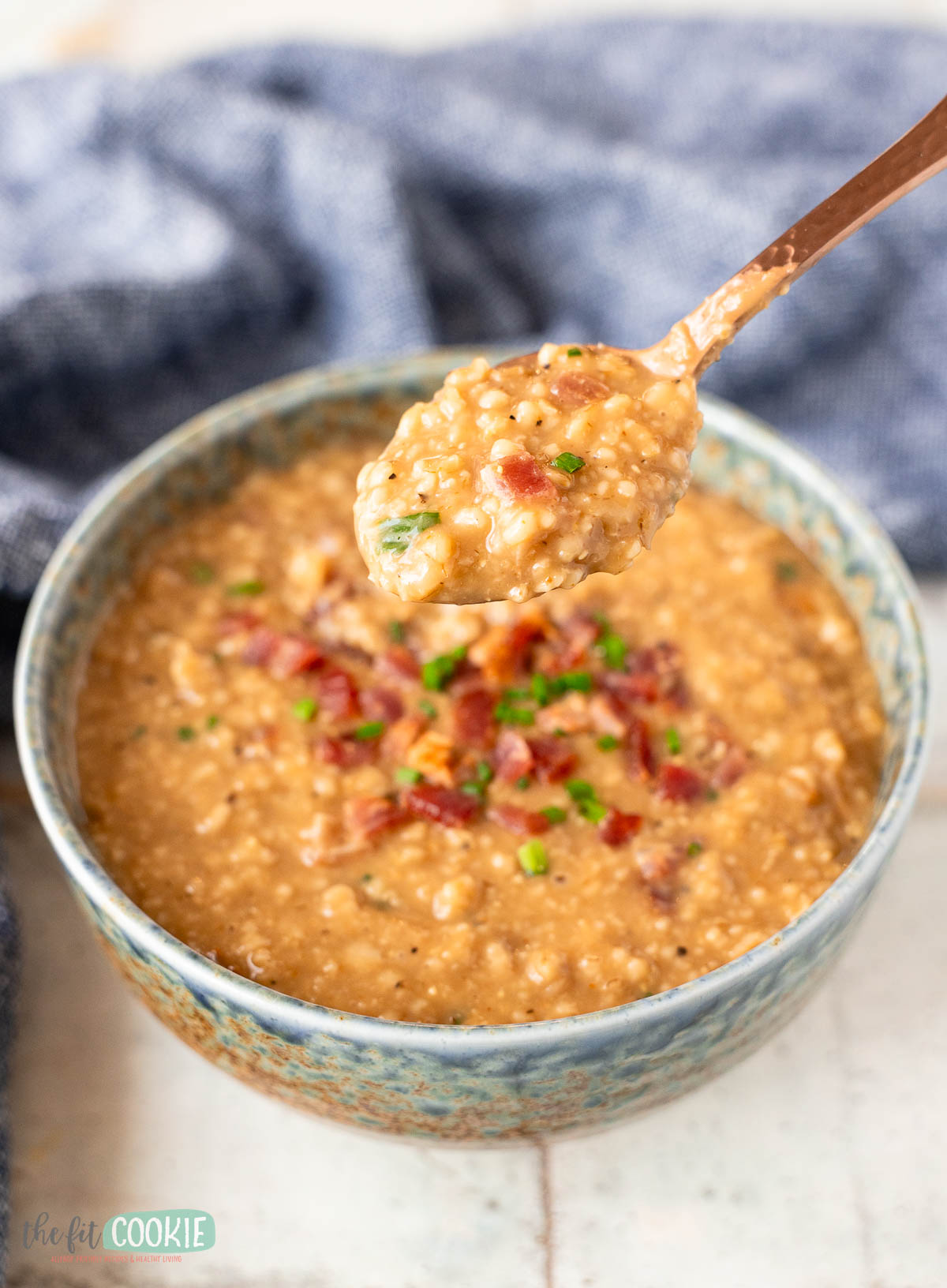 bowl of savory protein oatmeal porridge with a spoon lifted showing a close up of the oatmeal.